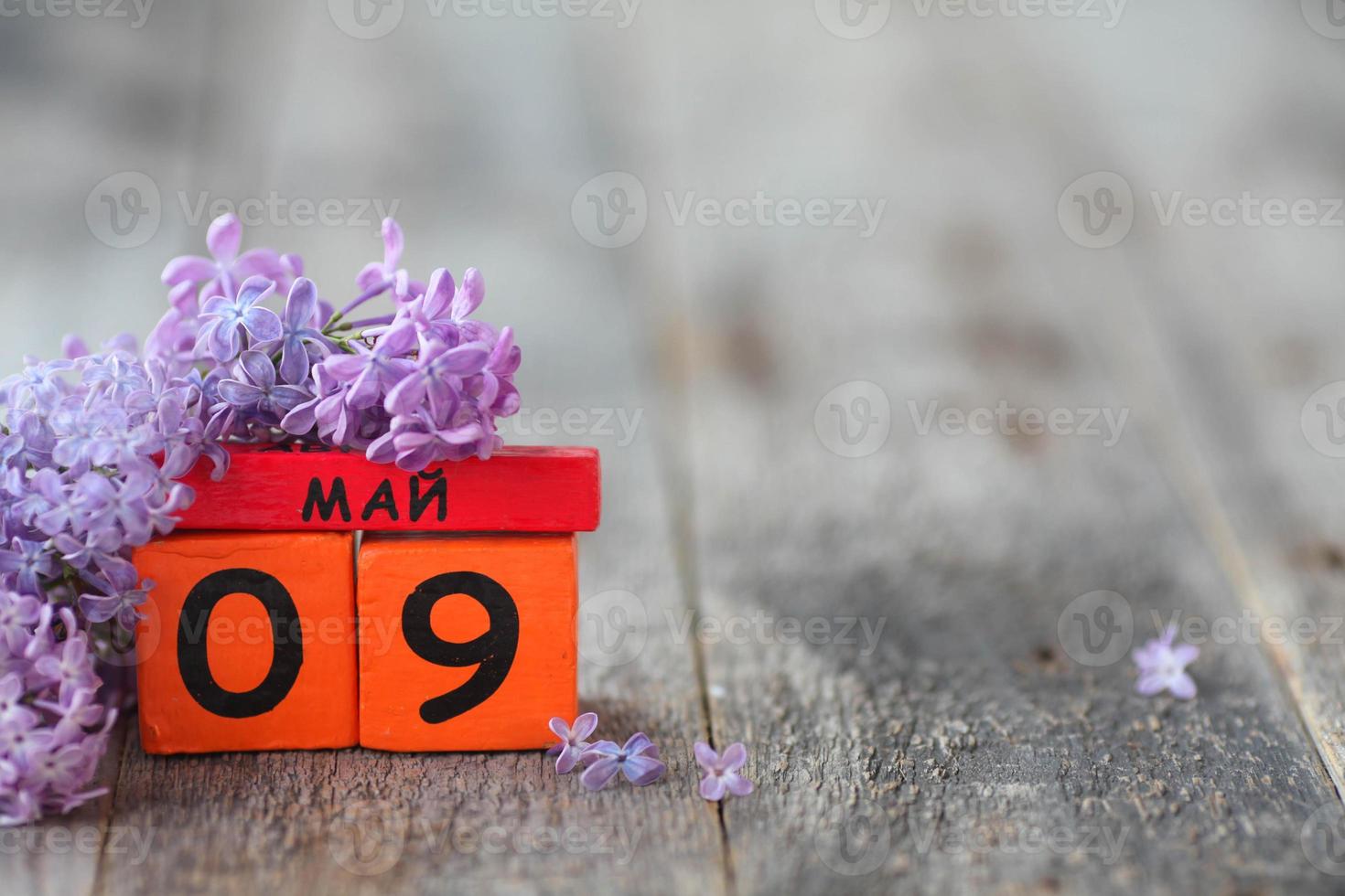 Wooden calendar with Russian text May 9 and a bouquet of lilacs on a wooden background. Victory Day. Copy space. photo