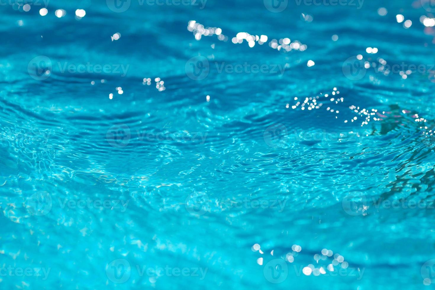 Close-up of blue water in the pool. Side view.  Bokeh light background in the pool. photo