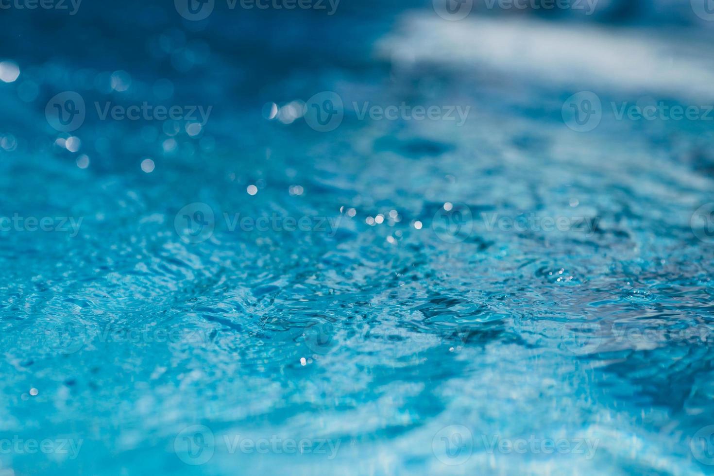 Close-up of blue water in the pool. Side view. Bokeh light background in the pool. photo