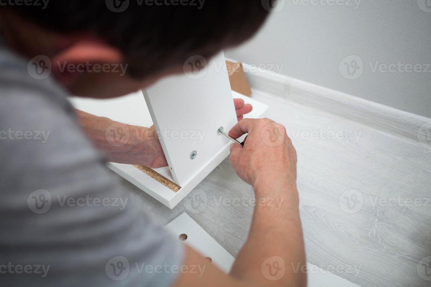 Close up of man hand, furniture assembler make flat  pack white furniture assembly service at home. photo