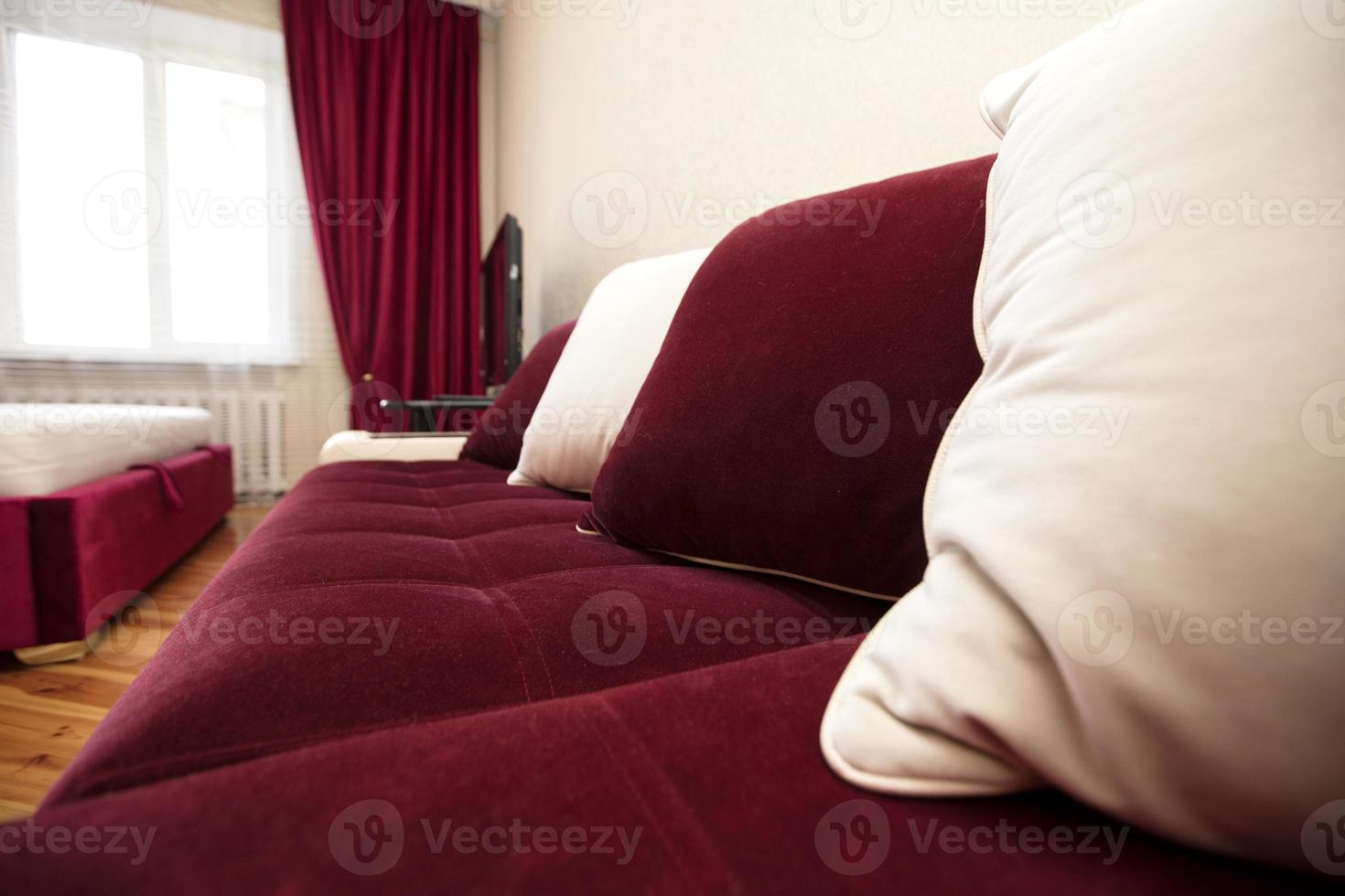Part of a red sofa with white pillows in the living room. photo