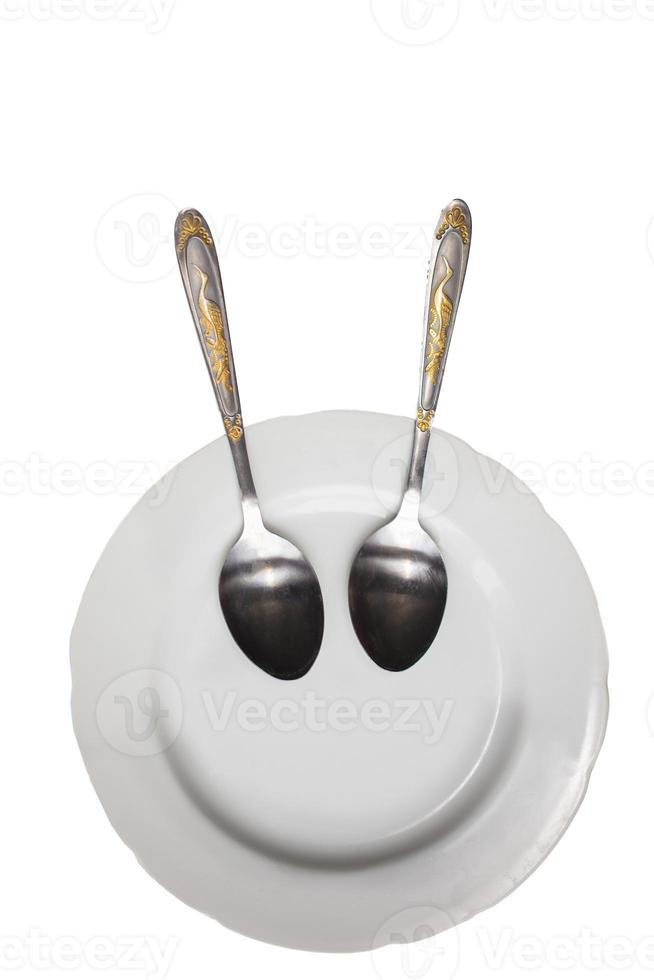 Plate with spoons on a white background. Funny dishes. Plate with a smile. photo