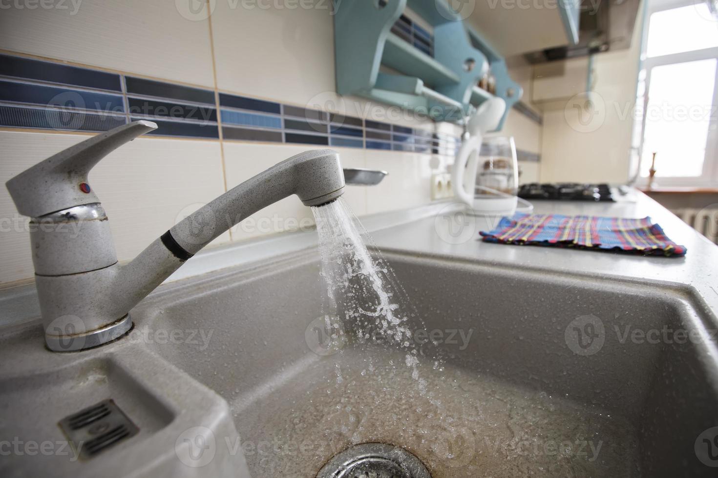 In the kitchen, water flows from a faucet into the sink. photo