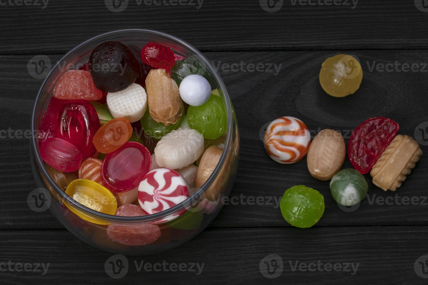 Candies in a jar on a dark background. Multi-colored caramel on a wooden board. Sweets. photo