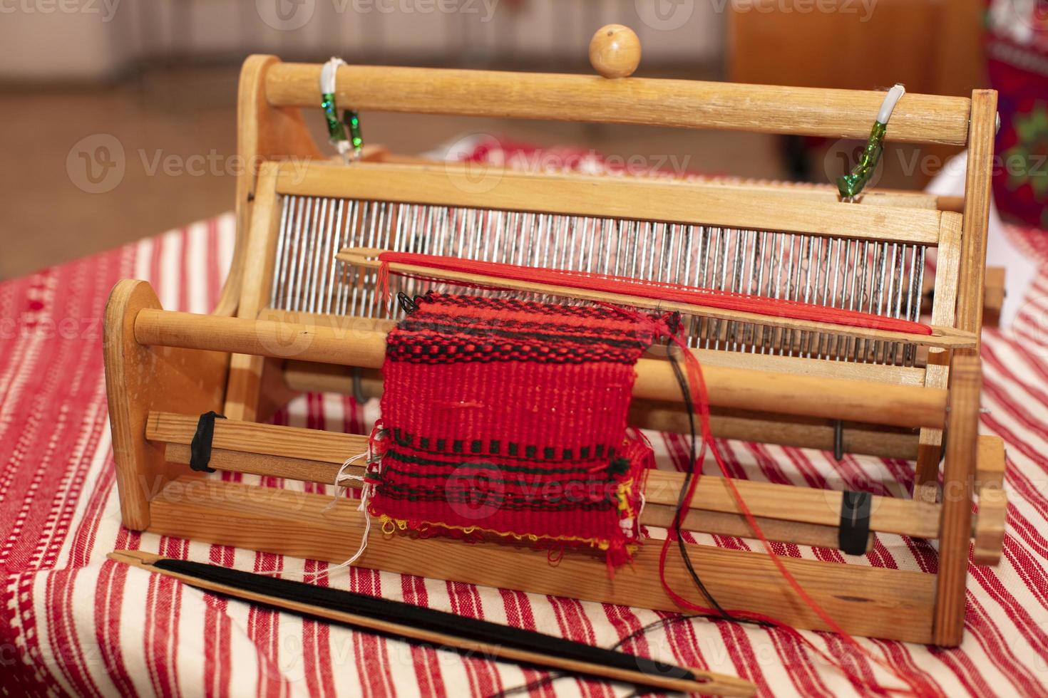 Spinning machine. An old wooden spinning wheel on a table with an embroidered shirt. photo