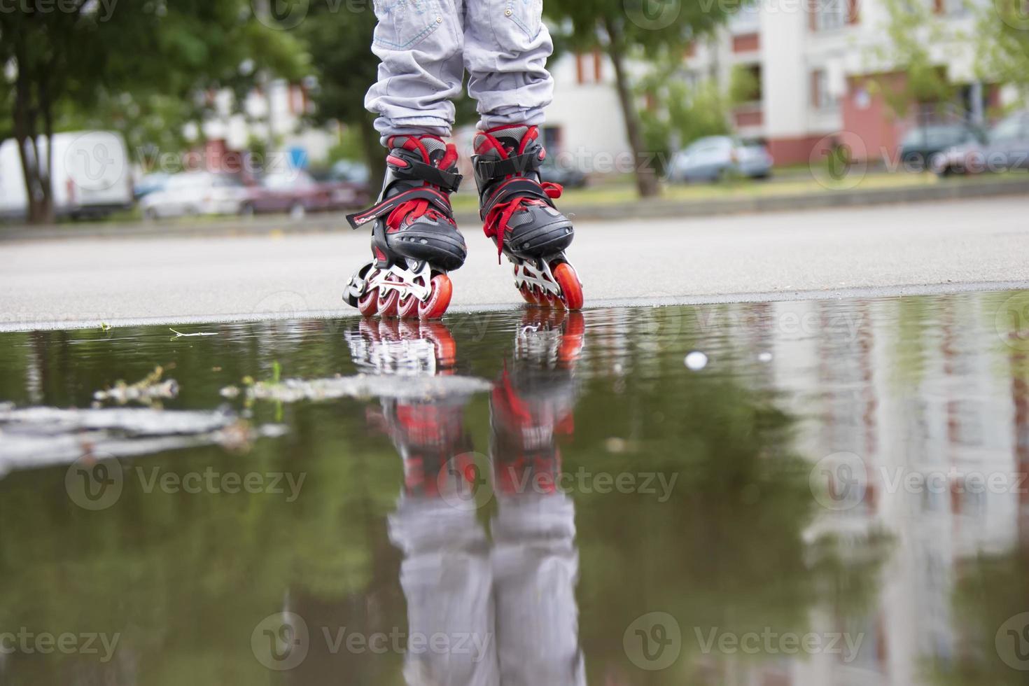 Roller skating. Legs in roller skates ride through a puddle. photo