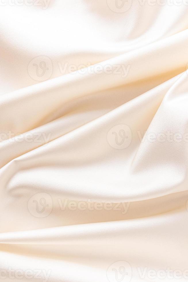 luxurious wedding satin background with delicate folds. elegant satin fabric of beige color, ivory. vertical view. photo