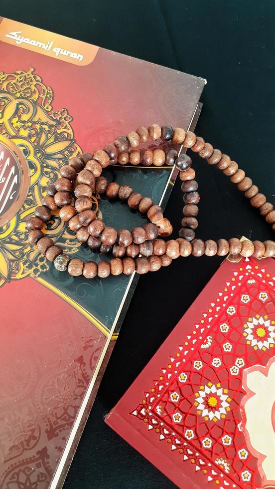 Al Quran and tasbih over black background. photo