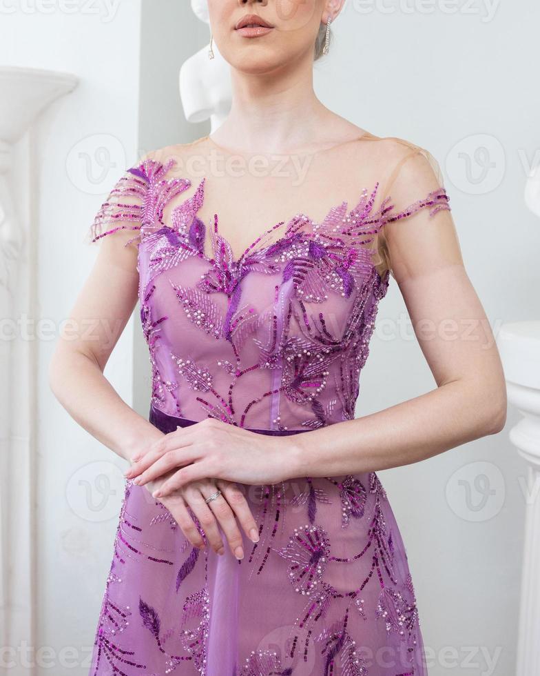 A woman in a purple dress stands in a room with a statue in the background photo