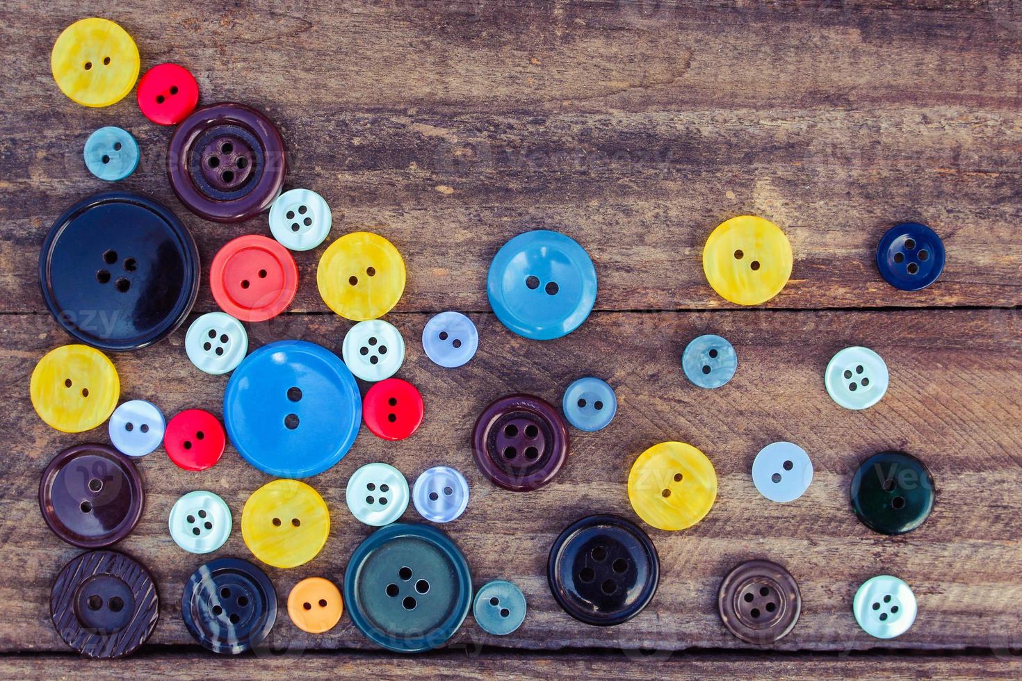 Lots of colorful buttons for clothes on wooden background. photo