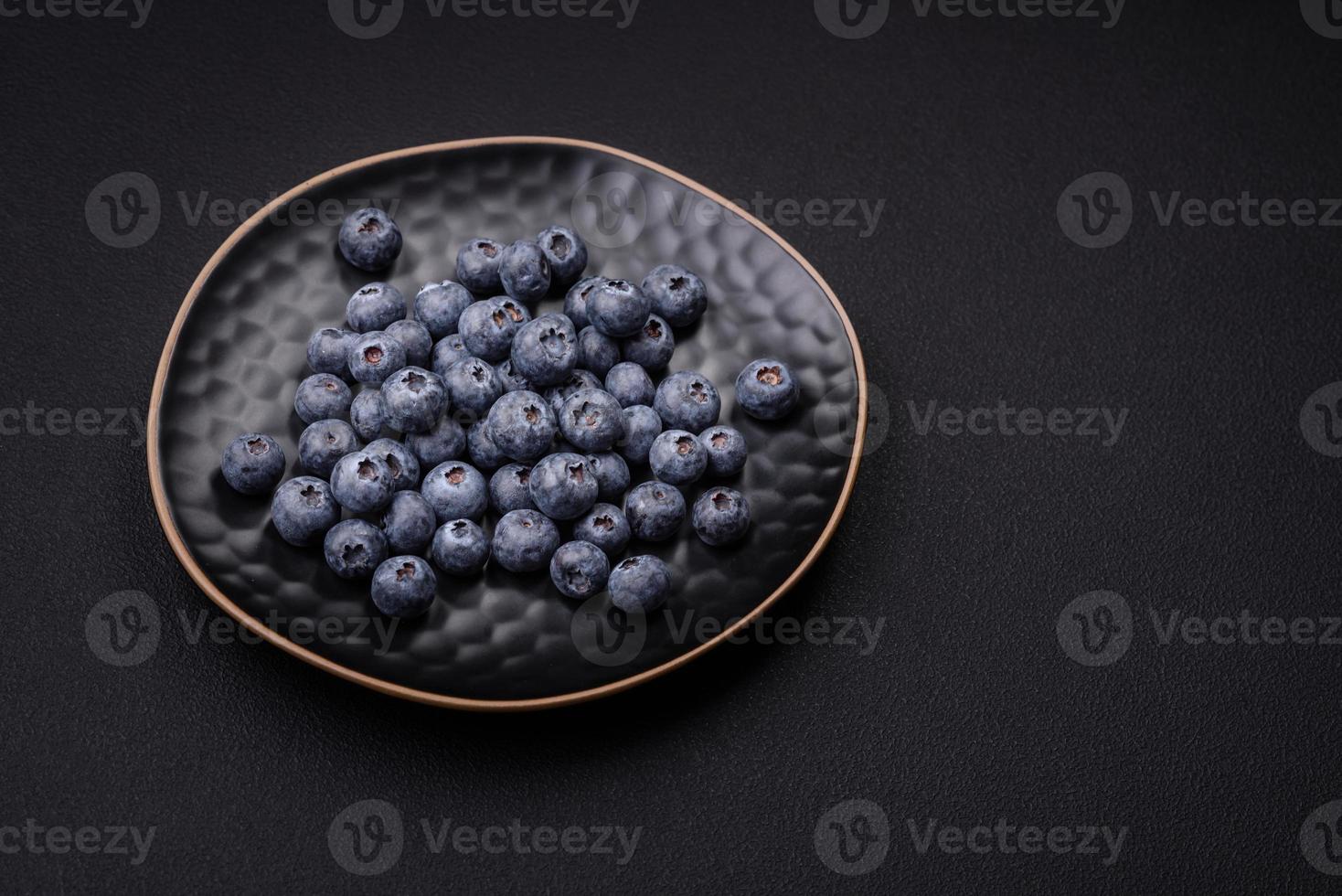 Delicious fresh blueberries on a textural black concrete background photo