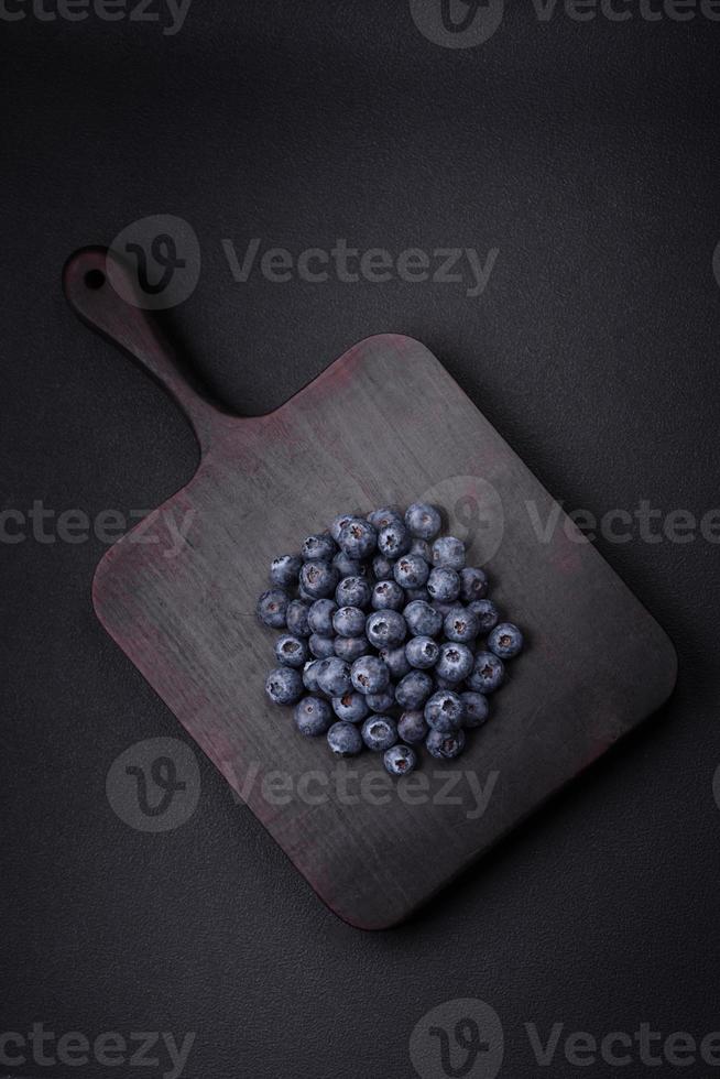 Delicious fresh blueberries on a textural black concrete background photo