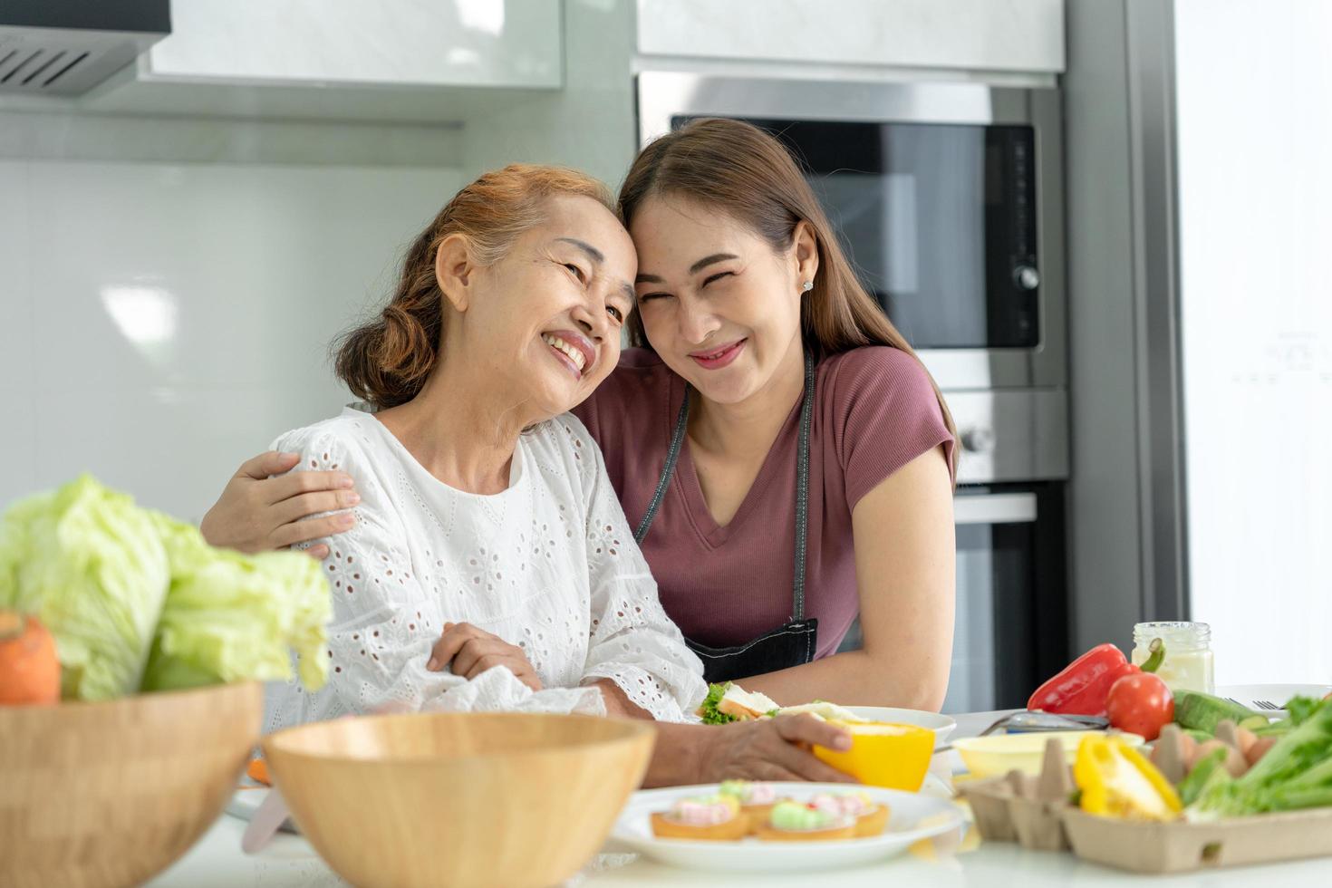 ocupaciones juntos durante el vacaciones. madre y hija son teniendo un comida juntos durante el vacaciones. asiático hembra preparar desayuno en mañana, disfrutar, fin de semana, vacante, familia tiempo, contento. foto