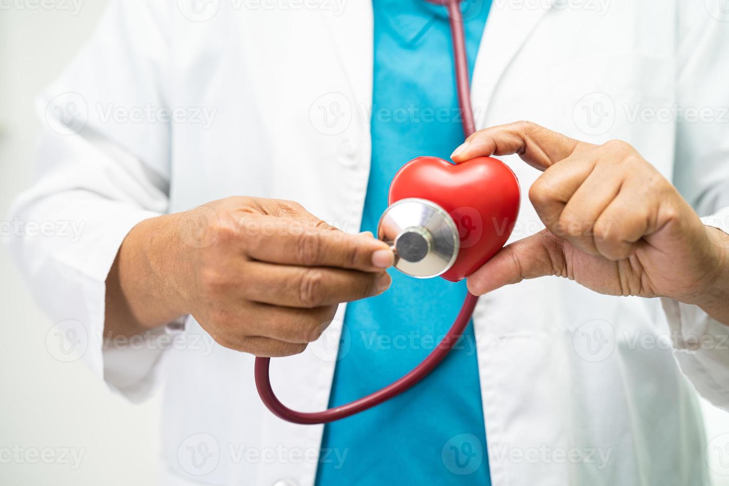 Doctor holding a red heart in hospital ward, healthy strong medical concept. photo