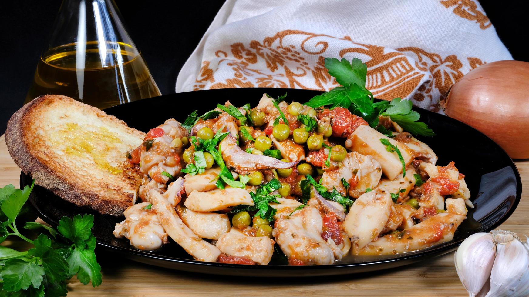 Cervia, Ravenna province, Italy March 23, 2023. Typical dish of the Romagna region made with cuttlefish and peas and also tomato. They are served with garlic-scented toasted bread. photo