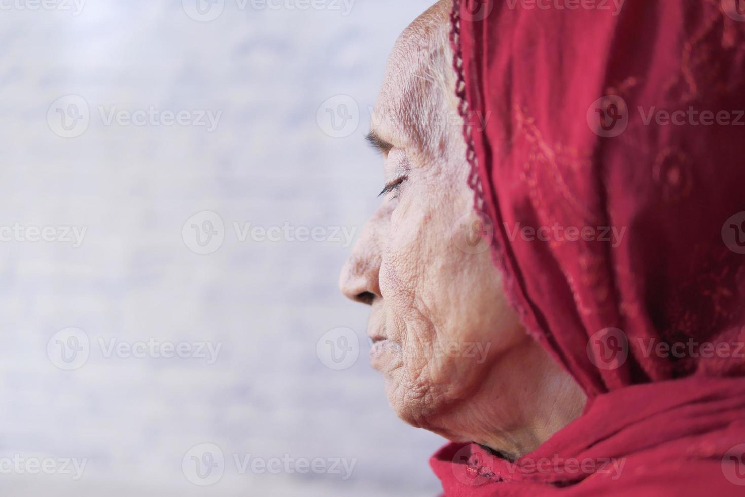 Depressed senior woman looking through window photo