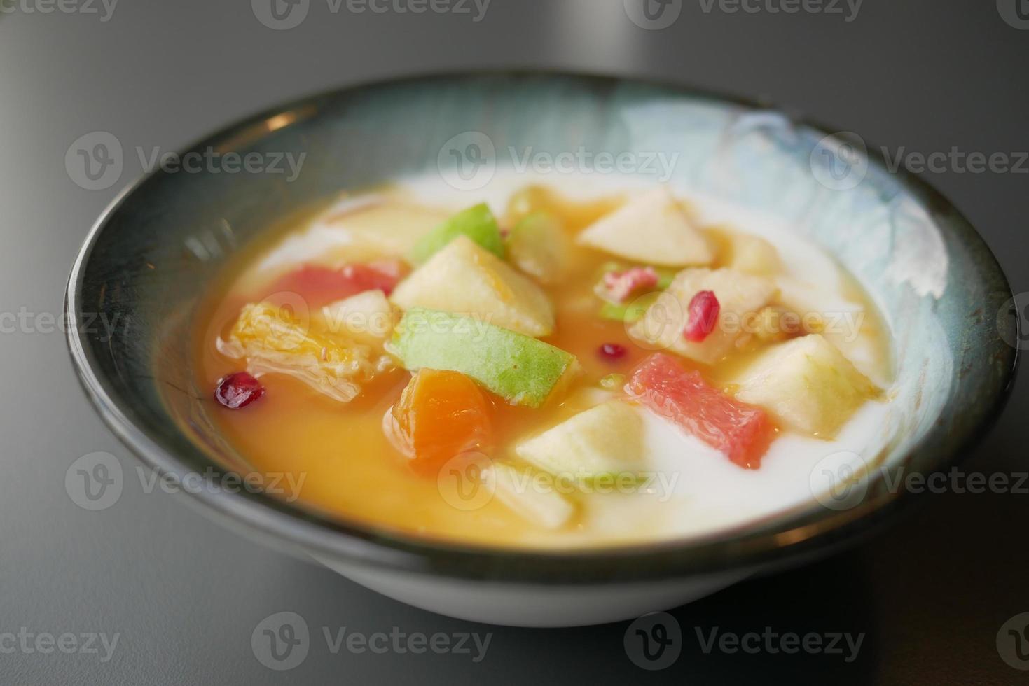 fresh fruits mixed with yogurt in a bowl on table photo