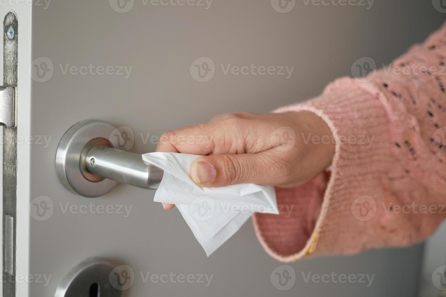 women hand cleaning door knob with tissue close up photo