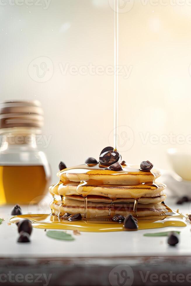 Syrup is poured down and chocolate chips are on top tall stack of golden pancakes layered on a plate with melted butter and syrup dripping down the sides of the stack. . photo