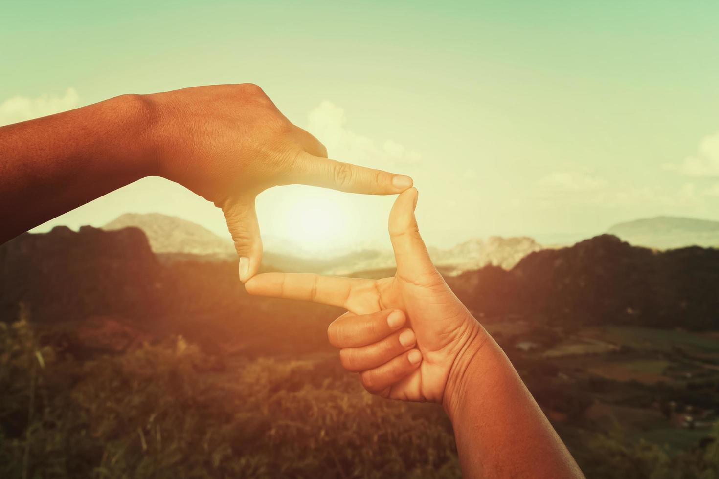 hand framing view distant over sunset. business concept photo