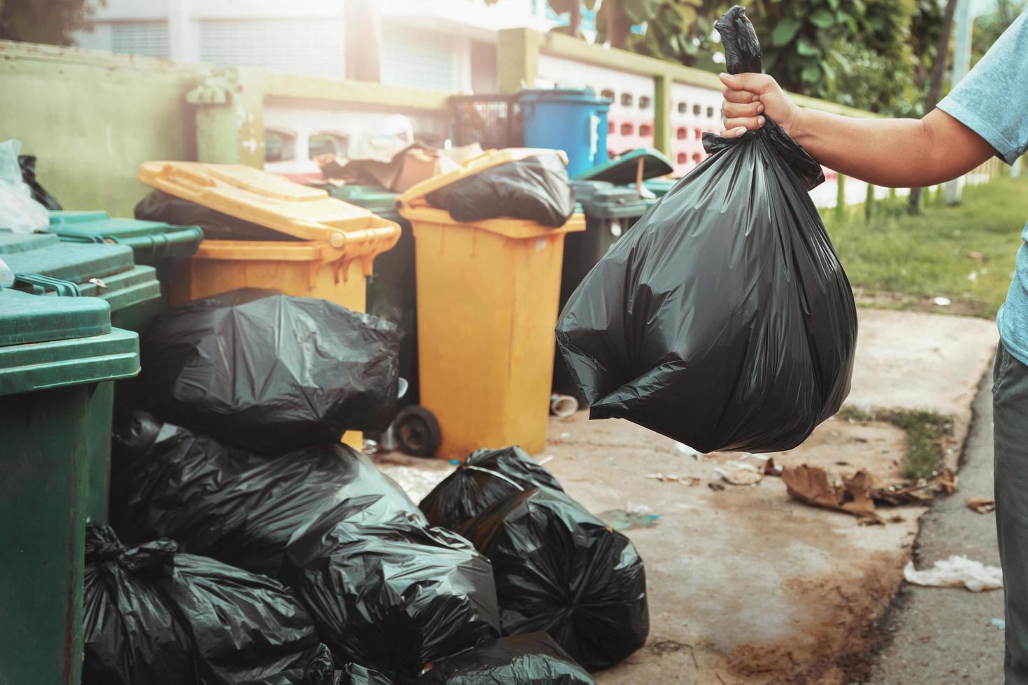 mujer mano participación basura en negro bolso para limpieza en a basura foto