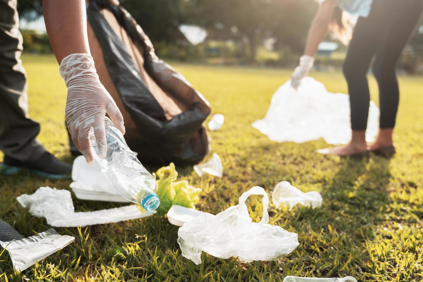 madre y niños acuerdo basura el plastico botella dentro negro bolso a parque en Mañana ligero foto