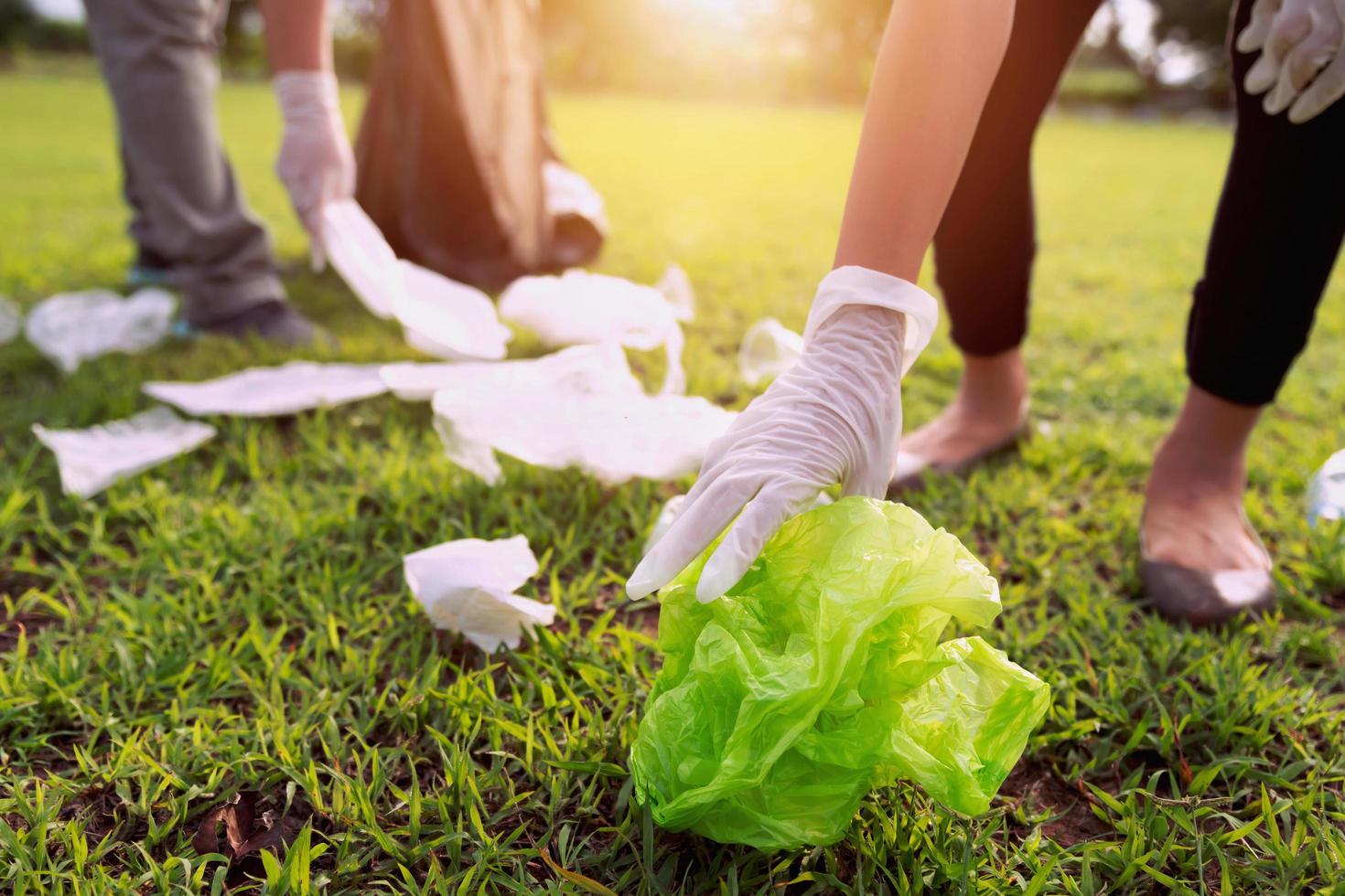 mother and children keeping garbage plastic bottle into black bag at park in morning light photo