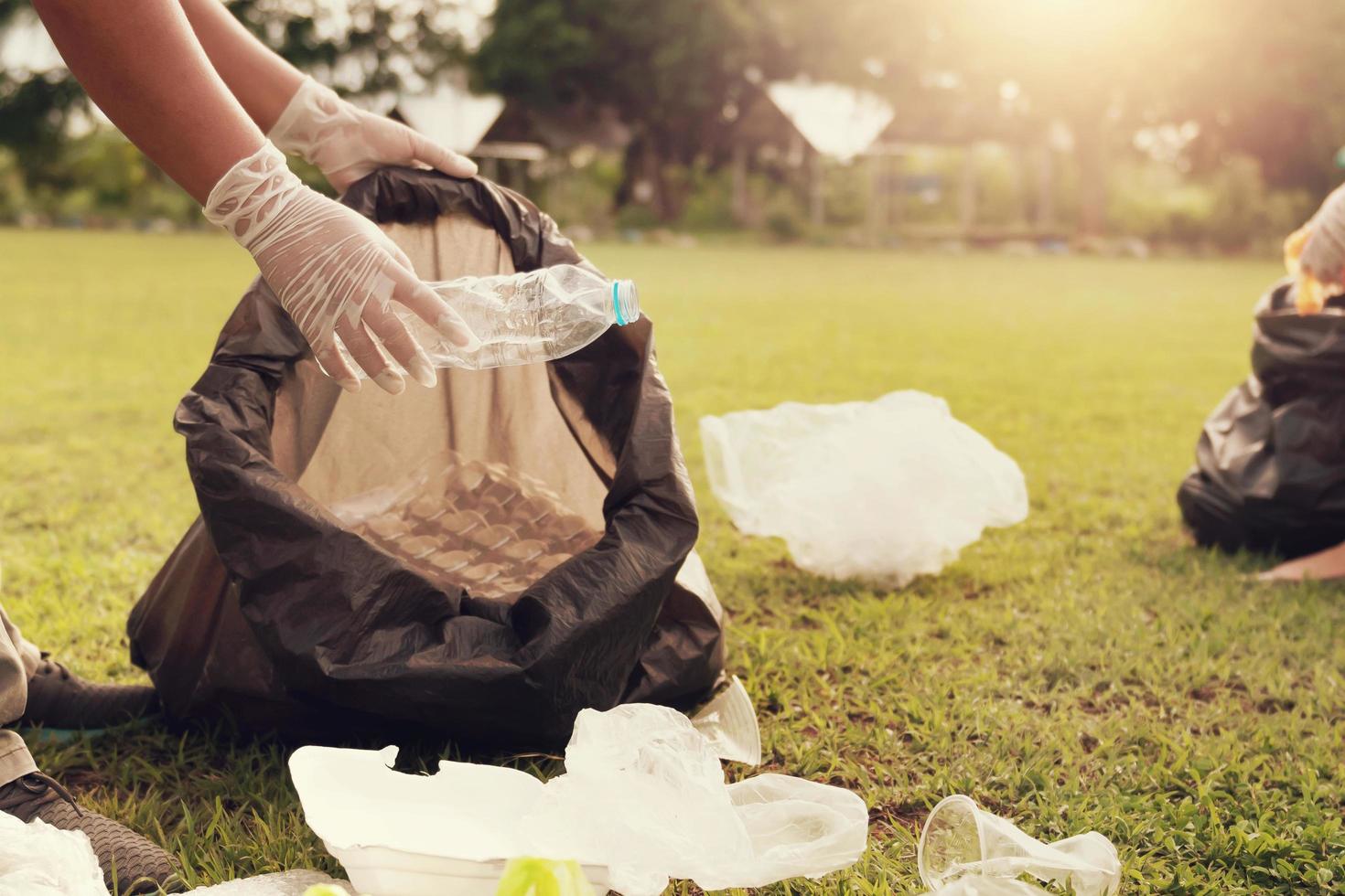 cerca arriba mano cosecha arriba basura el plastico para limpieza a parque foto