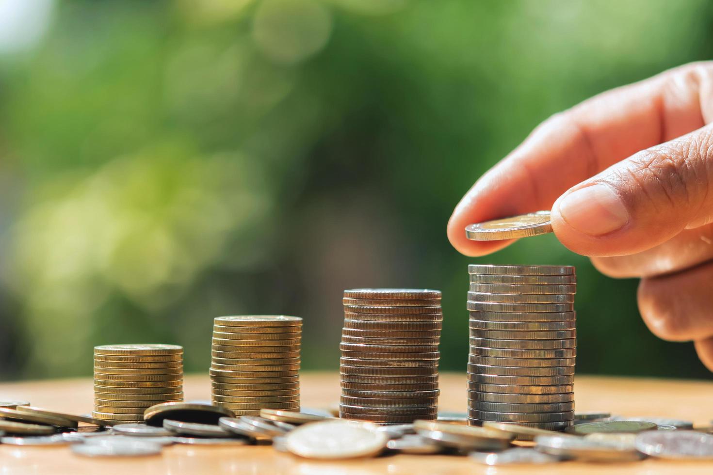 saving money hand putting coins on stack on table with sunshine. concept finance and accounting photo