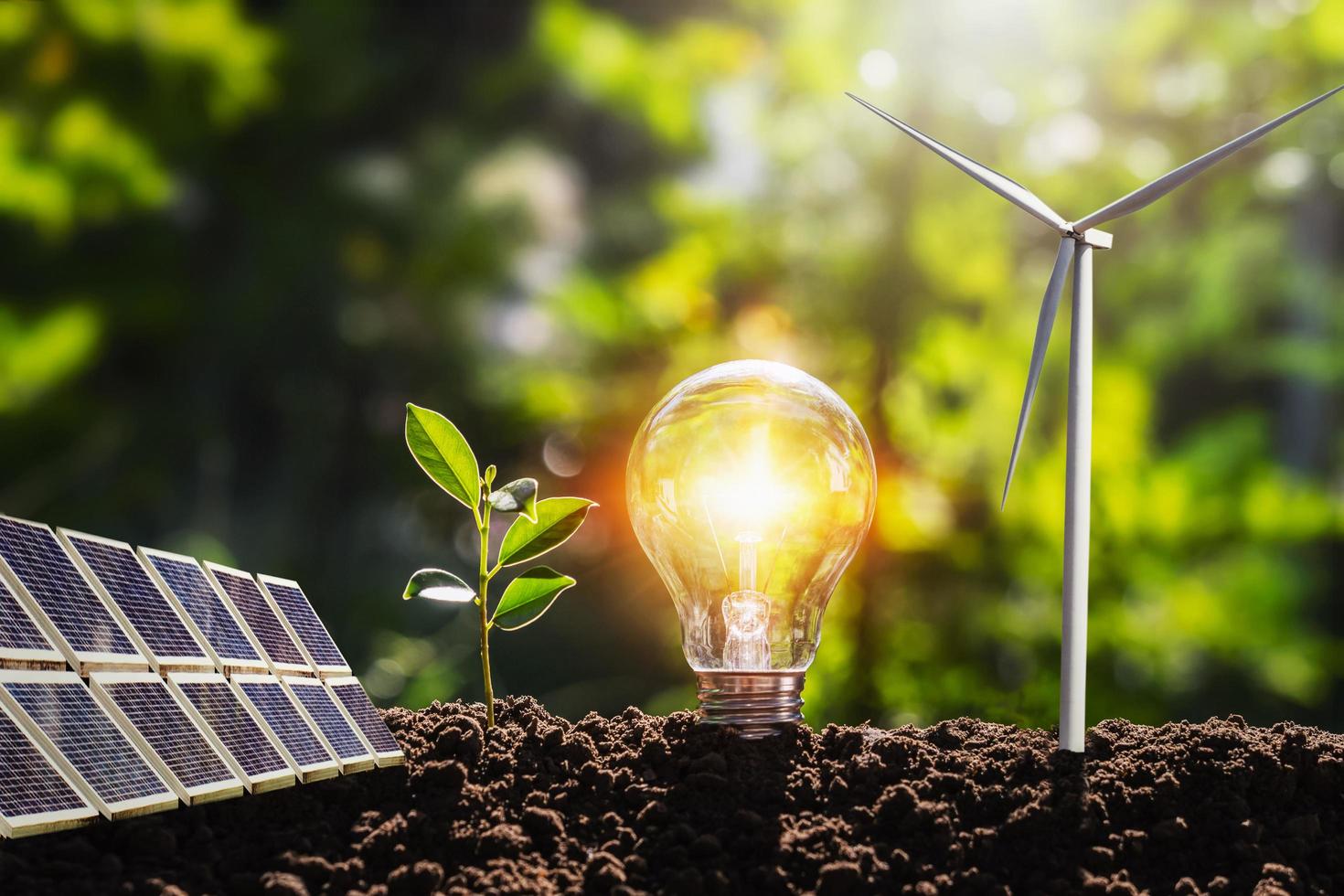 concepto idea limpiar energía en naturaleza. bombilla con solar panel y viento turbina en suelo foto