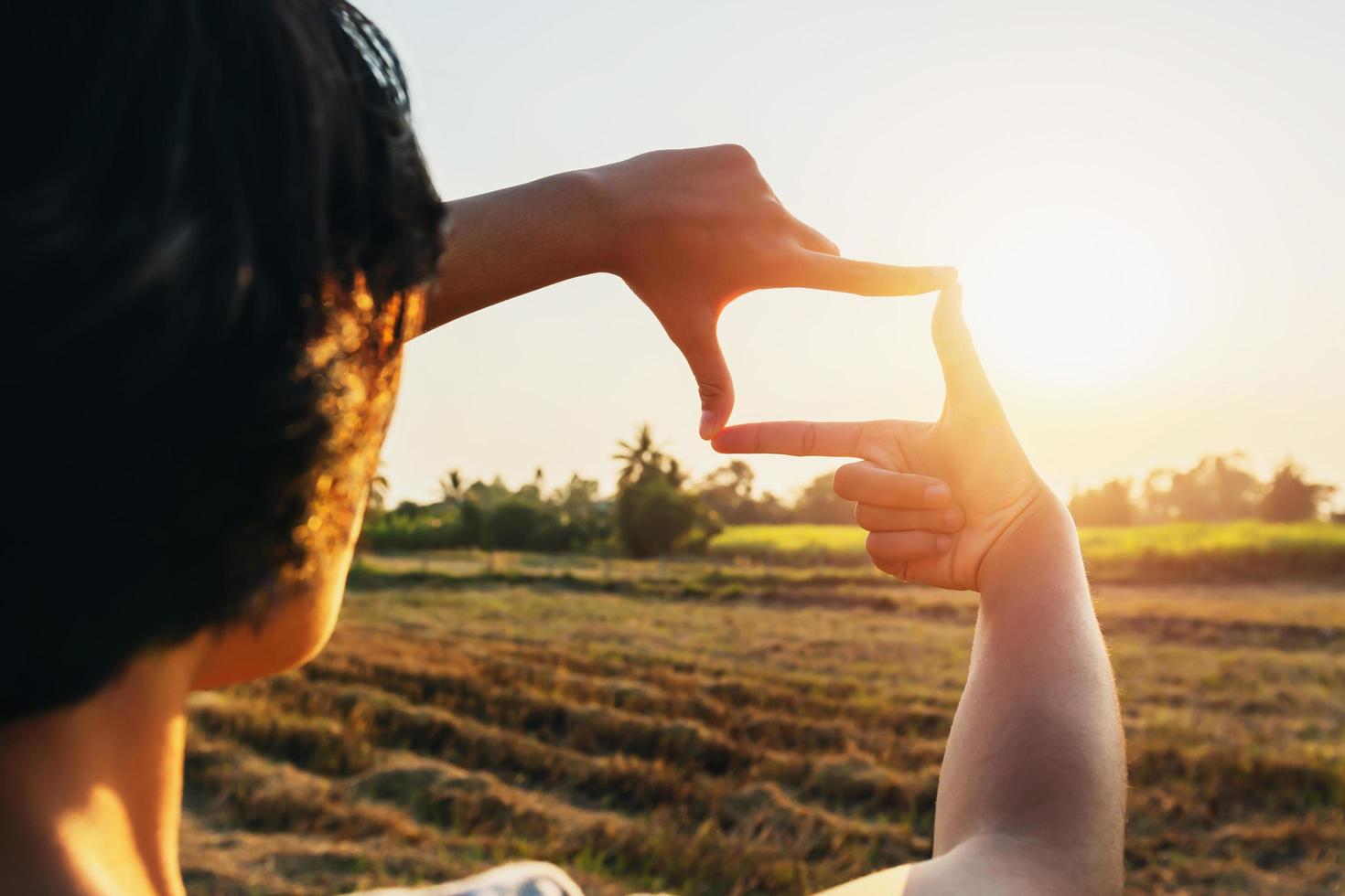 mujer mano enmarcado ver distante terminado puesta de sol. negocio concepto foto