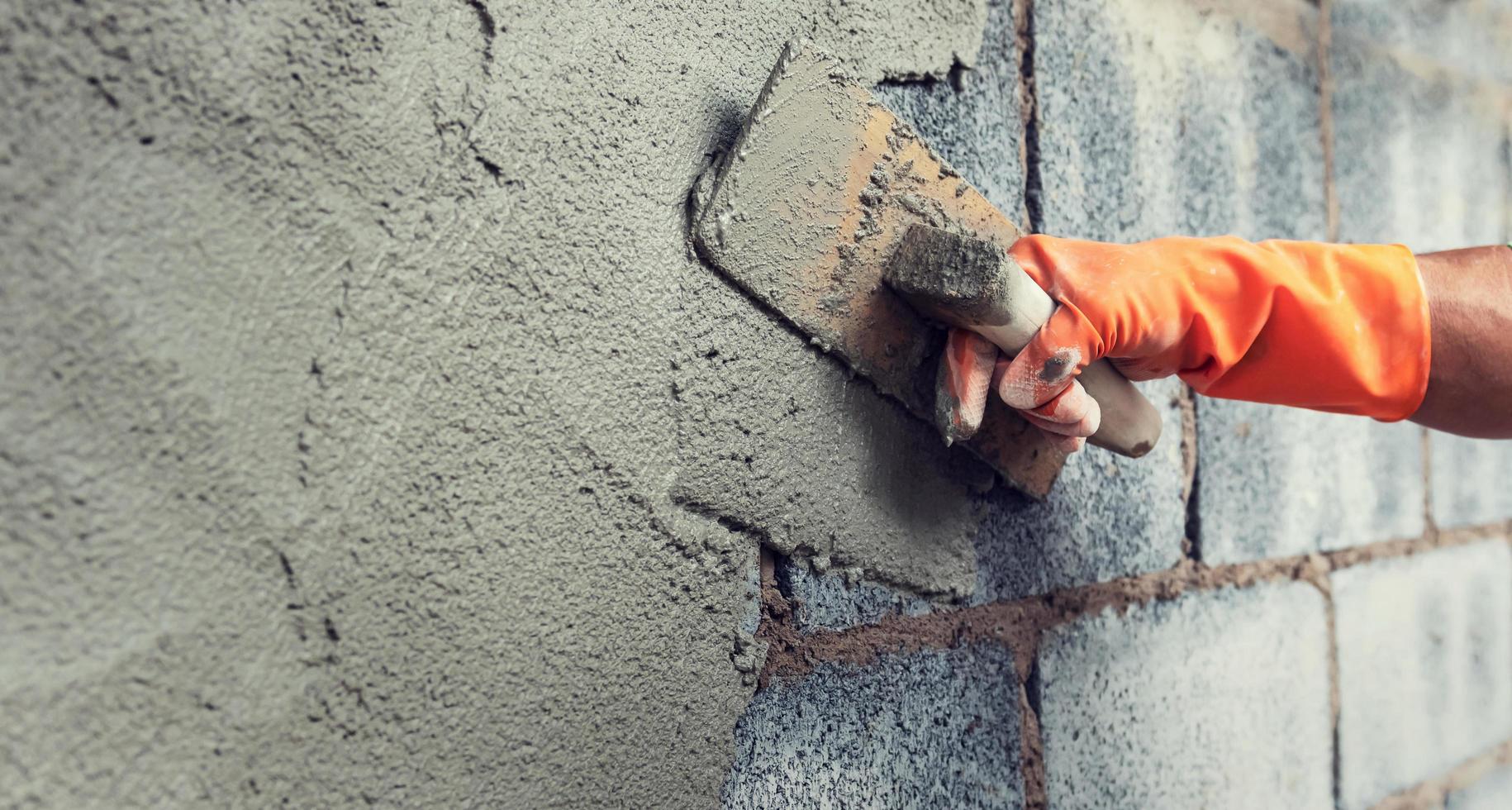 close up hand worker plastering cement on wall for building house photo