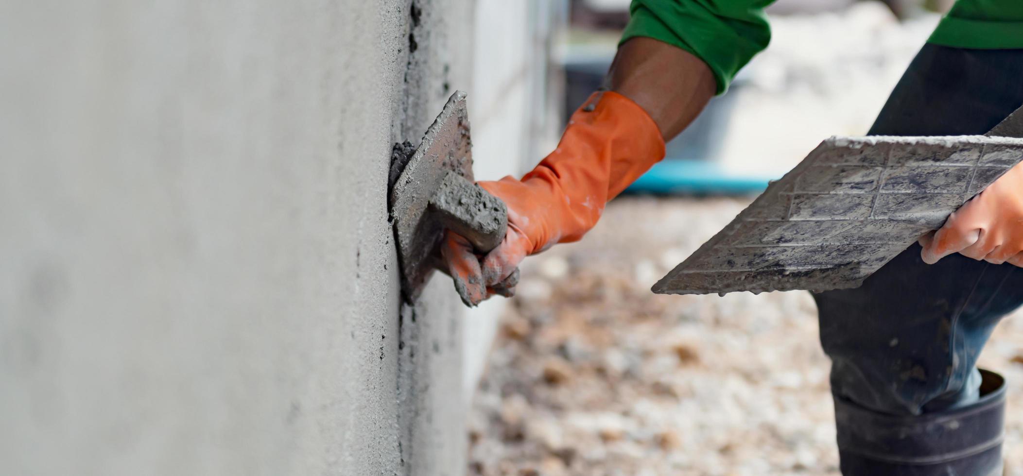 closeup hand worker plastering cement on wall for building house photo