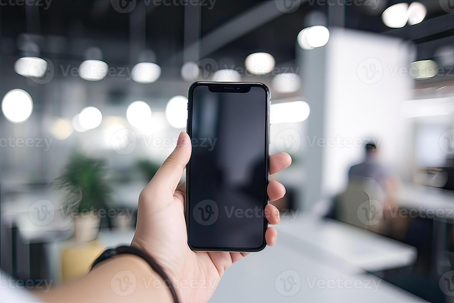 Close up view of hands holding mock up smart phone with modern office blurred background. photo