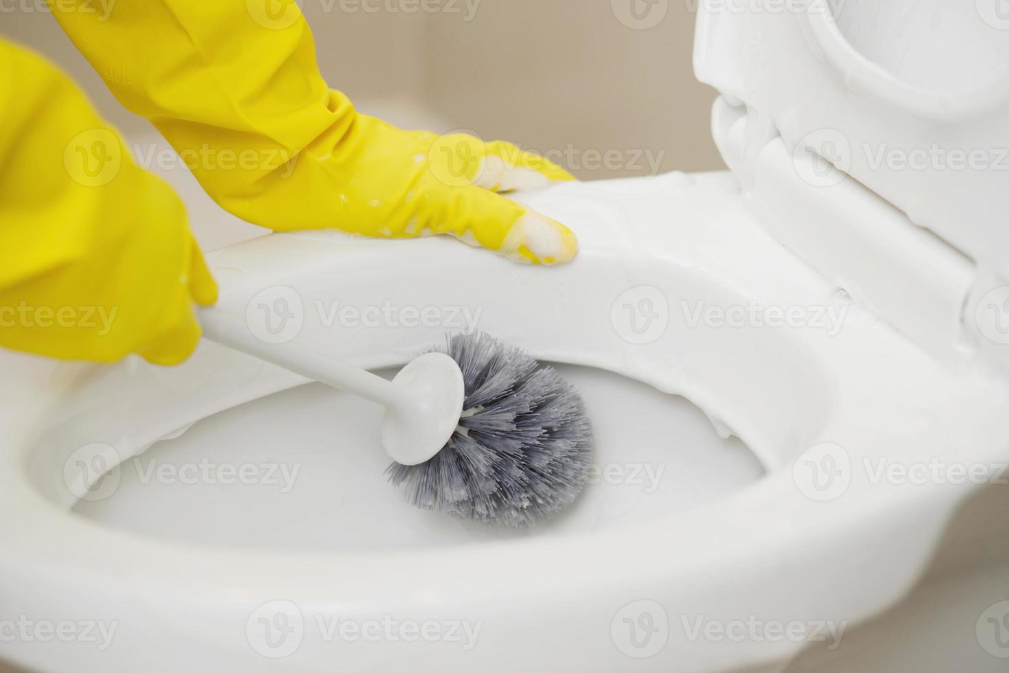 amas de casa utilizar un cepillo a limpiar el baño a eliminar suciedad y tomar cuidado de sanitario mercancía. foto