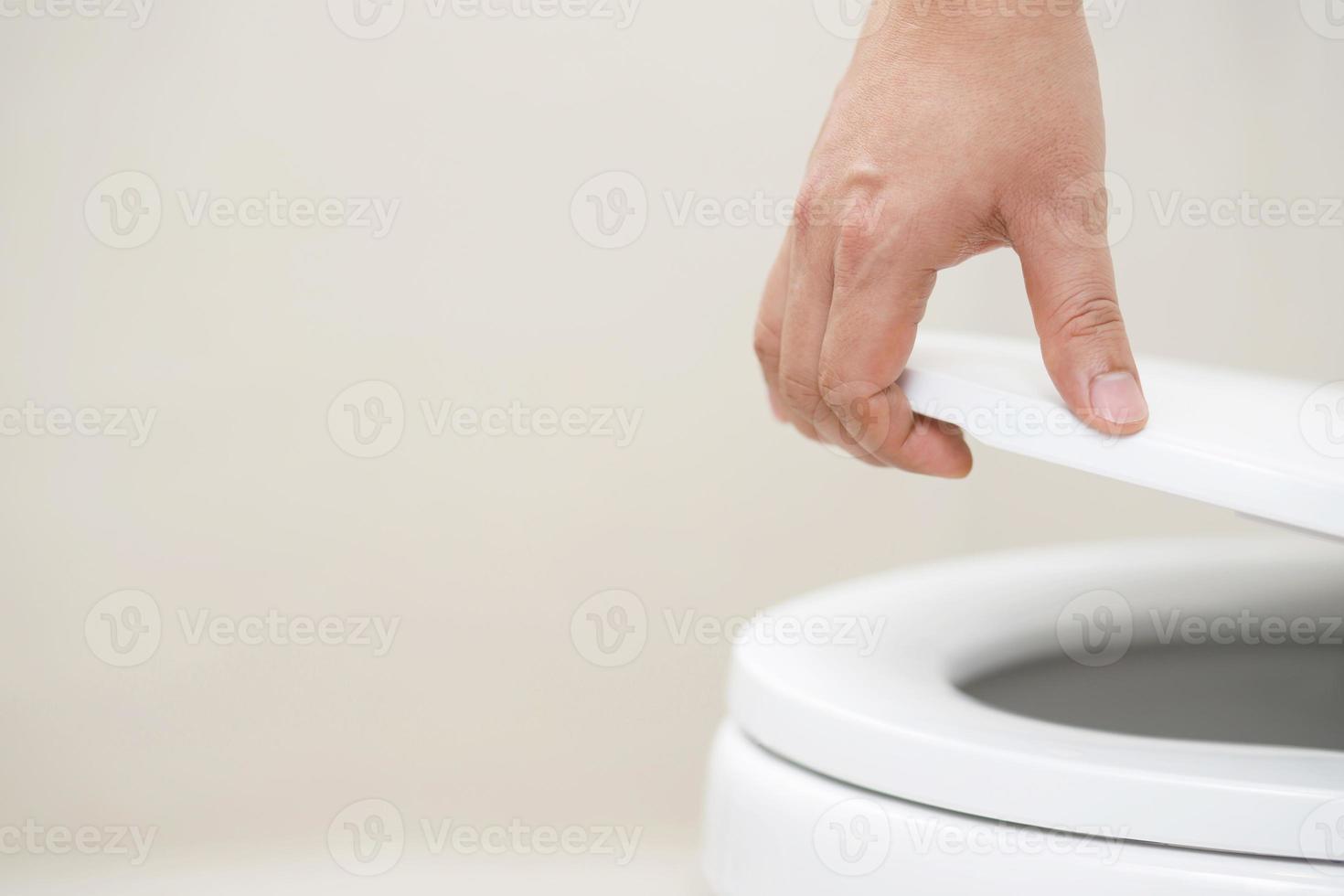 close up hand of a woman closing the lid of a toilet seat. Hygiene and health care concept. photo