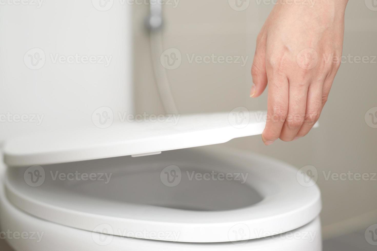 cerca arriba mano de un mujer clausura el tapa de un baño asiento. higiene y salud cuidado concepto. foto