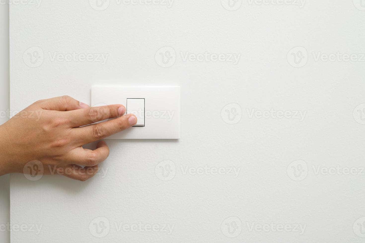 Turn off the light, close up finger man hand is closing the power switch with wall at home  to save energy. reduce global warming. photo