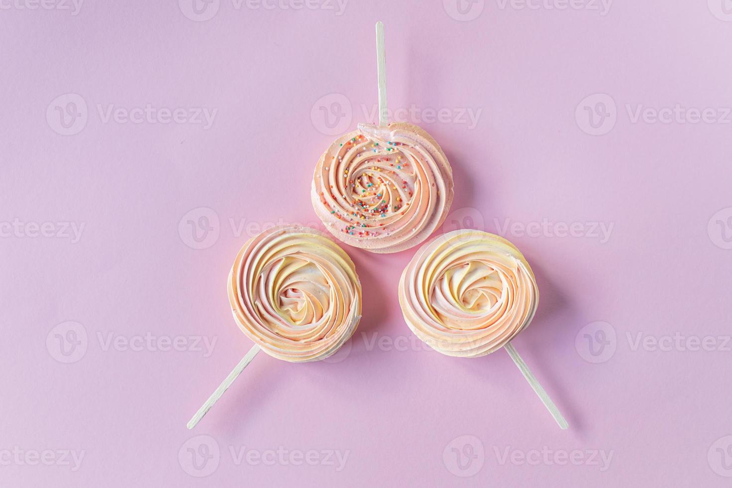 Pink round sweet meringues with decor lie on a pink background photo