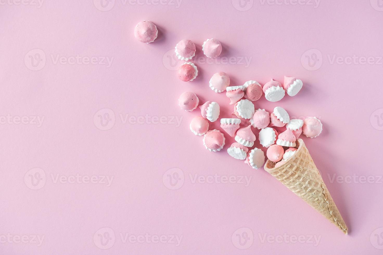 Colorful bright meringues in waffle cookies lie on a pink background photo
