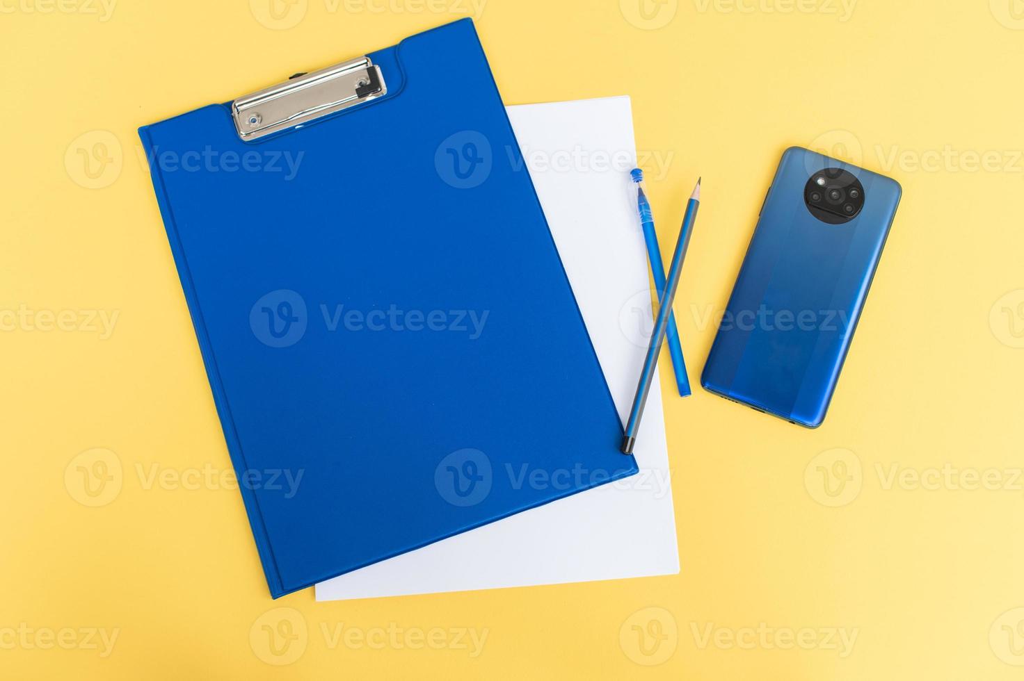 A blue stationery set as a template with a place to copy on a yellow background with a blue phone. photo