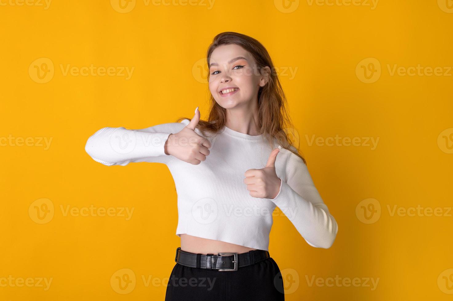 Young caucasian happy woman showing thumbs up on bright yellow background photo