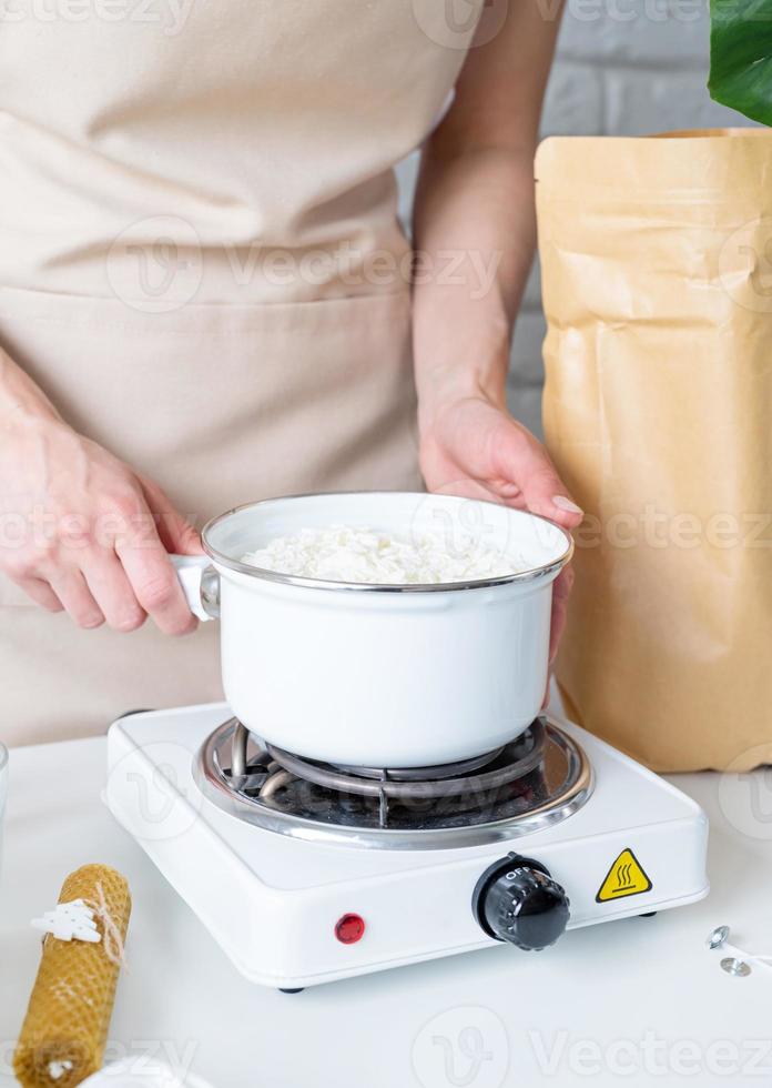 Woman making decorative aroma candles from soy wax photo