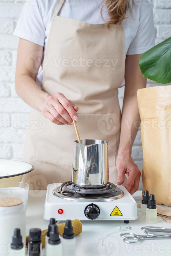 Woman making decorative aroma candles at table photo