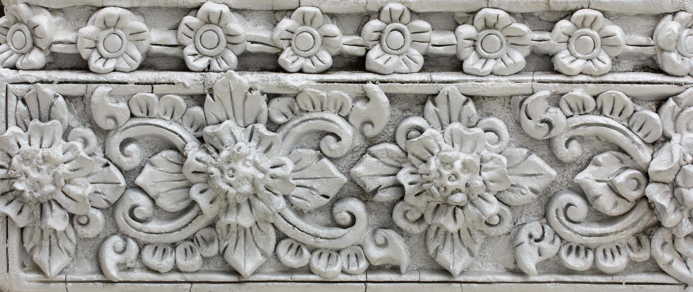 Pattern of gray flower carved on stucco design of native wall, Thai style in temple photo