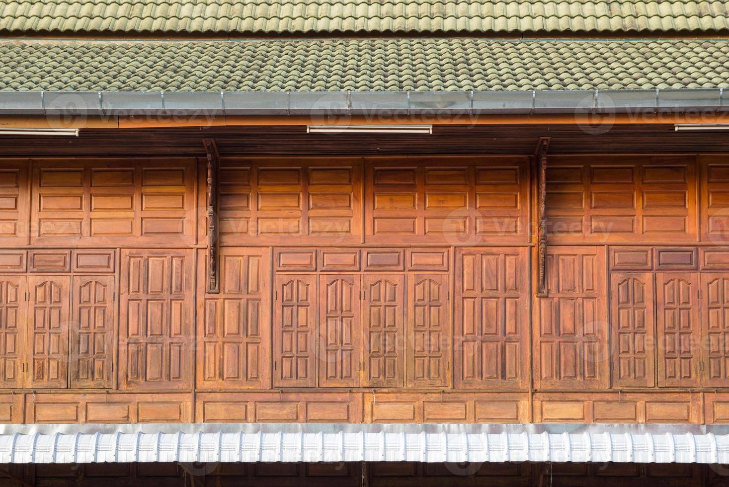 Front view of wooden window with roof tiles, facade of wooden house photo