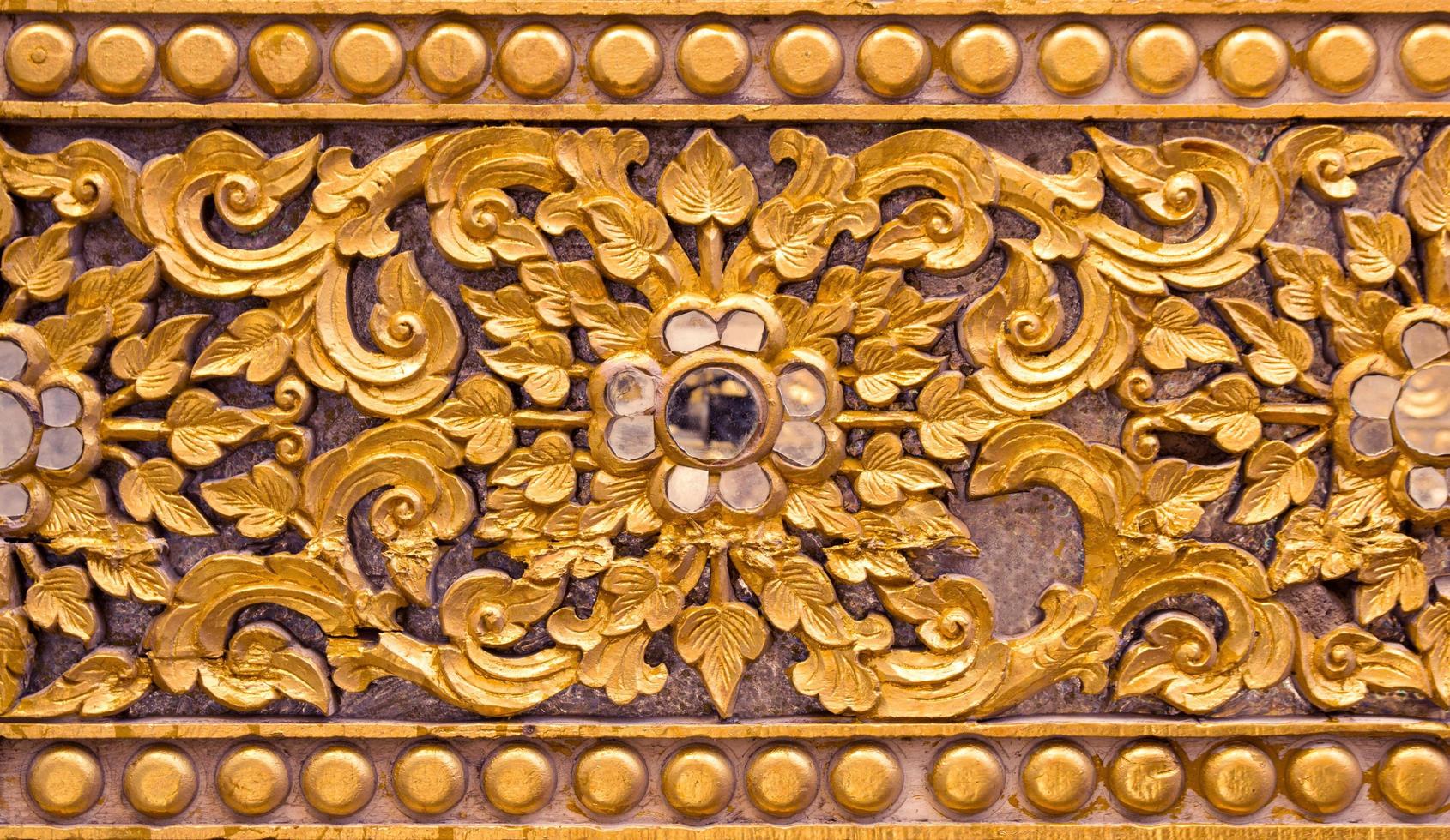 Pattern of gold flower carved on stucco design of native wall, Thai style in temple photo
