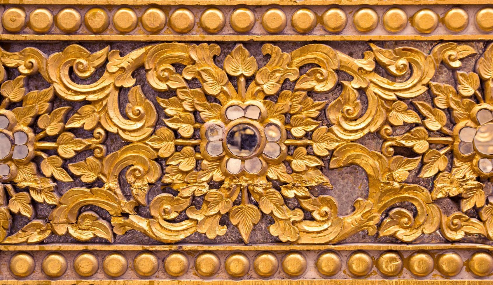 Pattern of gold flower carved on stucco design of native wall, Thai style in temple photo