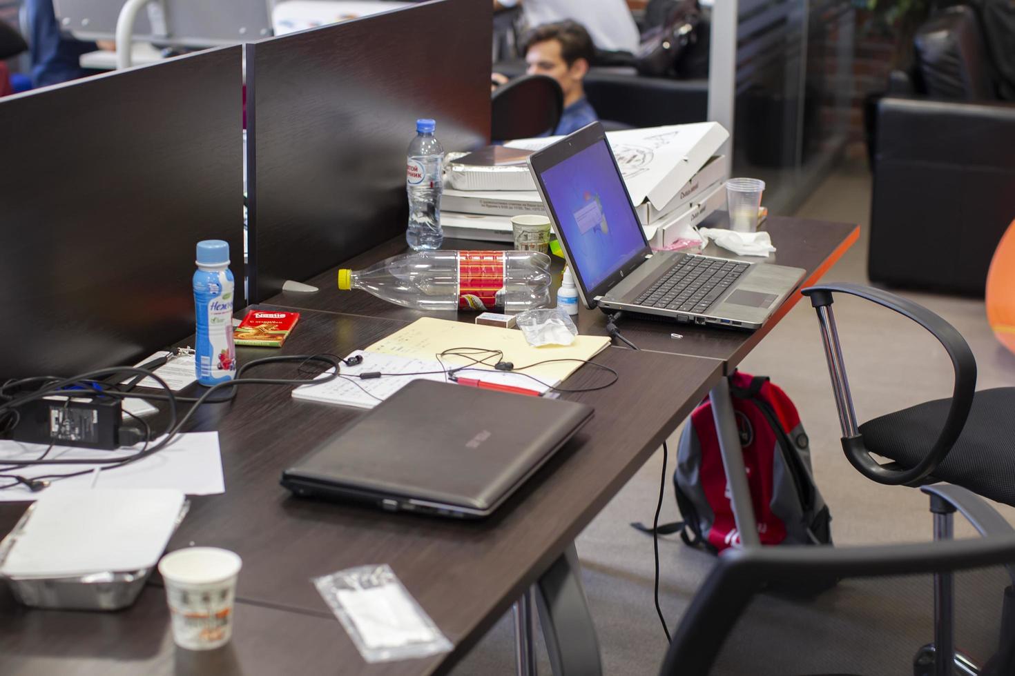 Belarus, the city of Minsk. Programmers Office. Workplace of the programmer.Office desk with laptops cups, leftover food. photo