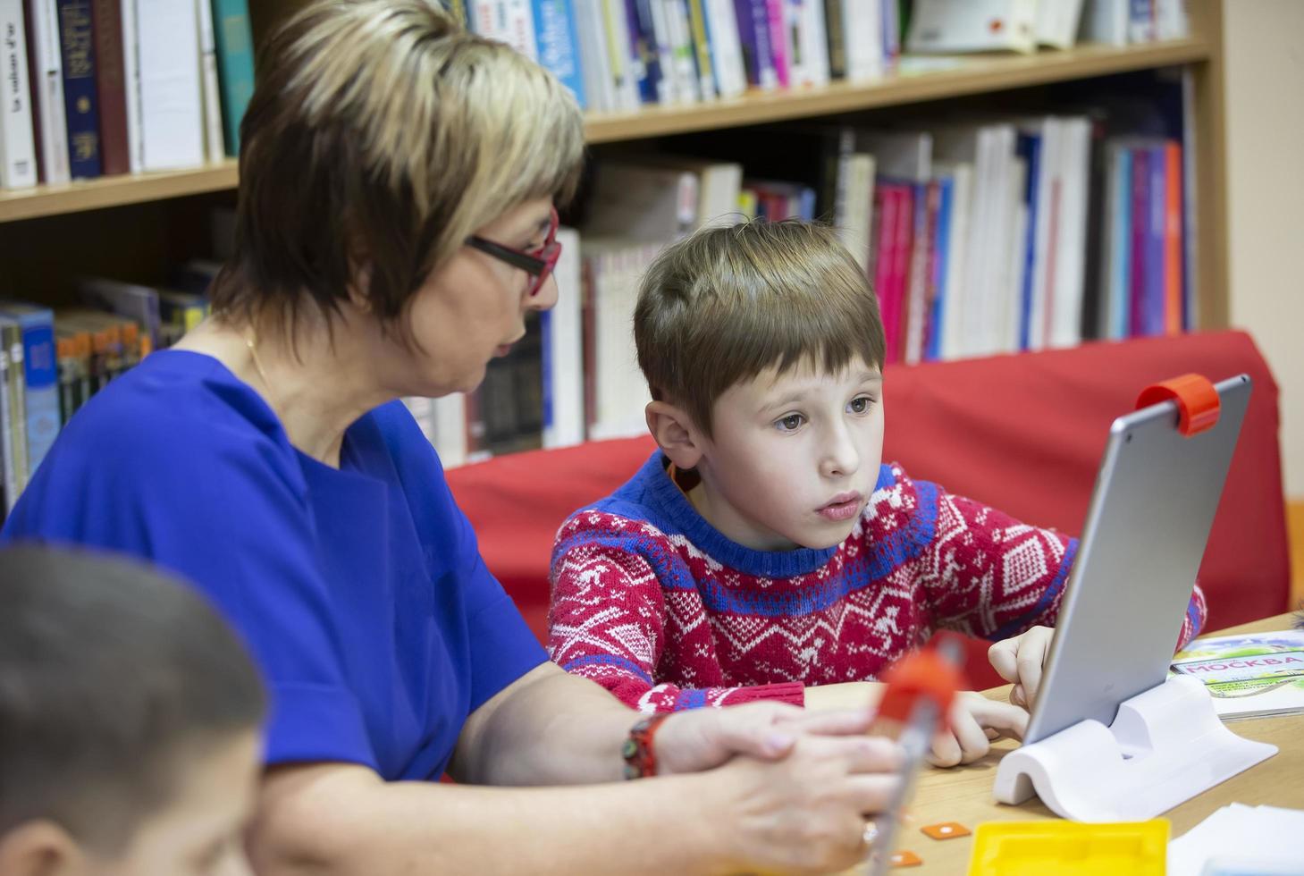 The child is studying with the teacher at the computer. Primary school student study at the tablet. photo